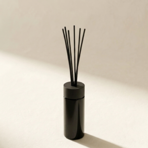 Reed Diffuser Clementine in dunkelviolettem Glas vor hellem citrus-cremefarbenem Hintergrund
