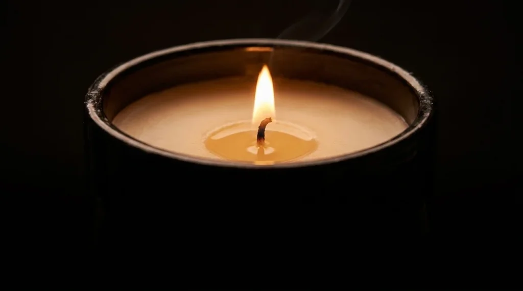 Handgemachte Drip of Infinity Duftkerze im schwarzen Keramikgefäß mit brennender Flamme und warmem Kerzenlicht.